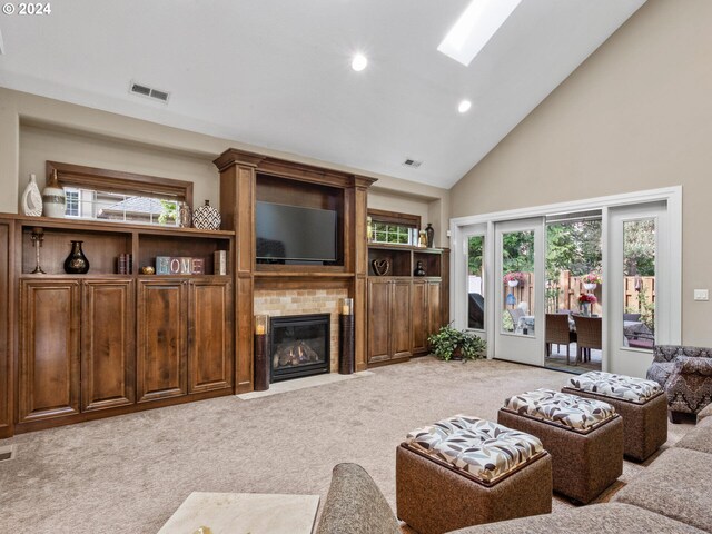 living room with light carpet, a brick fireplace, a skylight, and high vaulted ceiling