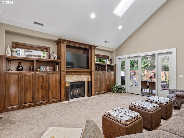 living room featuring visible vents, high vaulted ceiling, a skylight, a fireplace, and light colored carpet