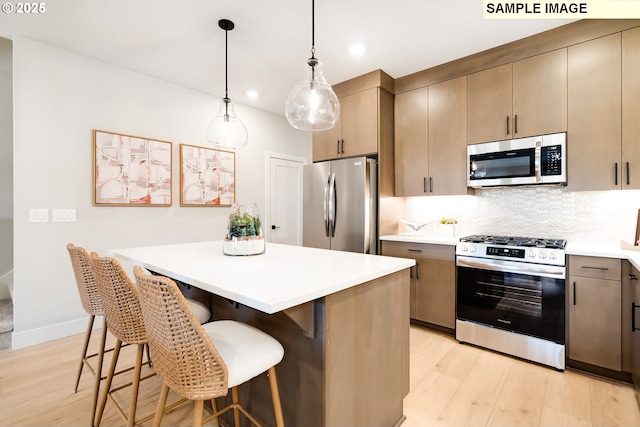 12100 SW Trask St, Beaverton, OR 97007 - kitchen with light wood finished floors, a center island, light countertops, appliances with stainless steel finishes, and decorative backsplash