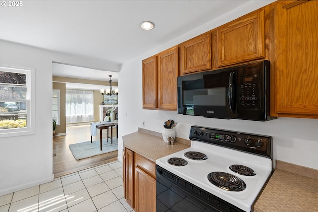 1013 NE Birchwood Dr, Hillsboro, OR 97124 - kitchen with range with electric cooktop, an inviting chandelier, brown cabinets, black microwave, and light countertops