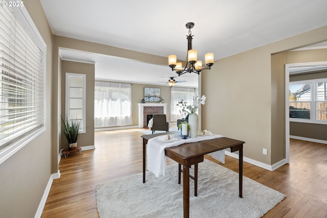 1013 NE Birchwood Dr, Hillsboro, OR 97124 - dining area featuring light wood-style flooring, a brick fireplace, baseboards, and ceiling fan with notable chandelier
