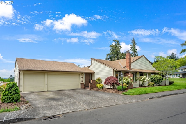 single story home with a front lawn, brick siding, a garage, a chimney, and driveway