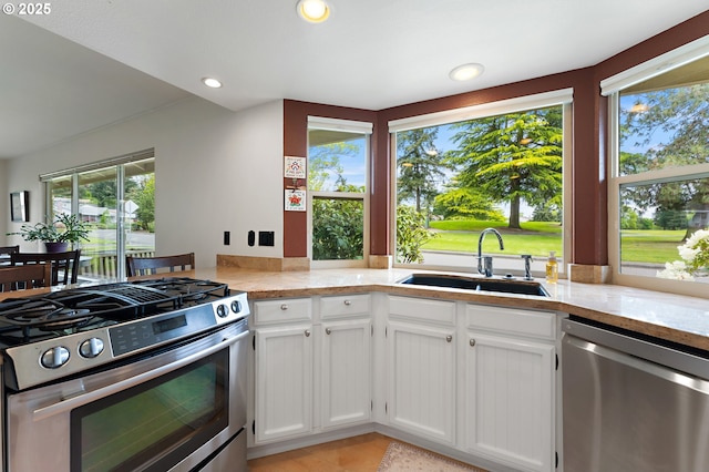 kitchen featuring recessed lighting, white cabinets, light stone counters, a sink, and stainless steel appliances