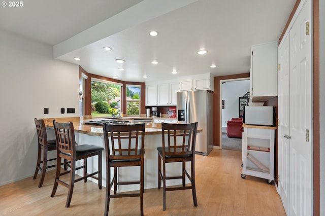kitchen with stainless steel appliances, recessed lighting, light wood finished floors, and a peninsula