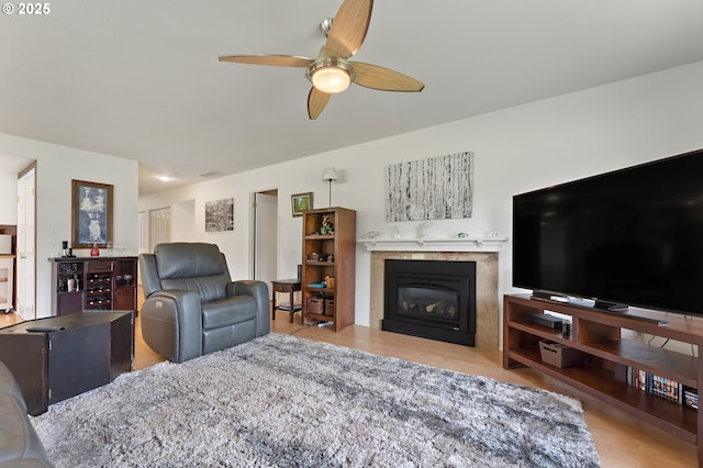 living area featuring ceiling fan, a fireplace, wood finished floors, and visible vents