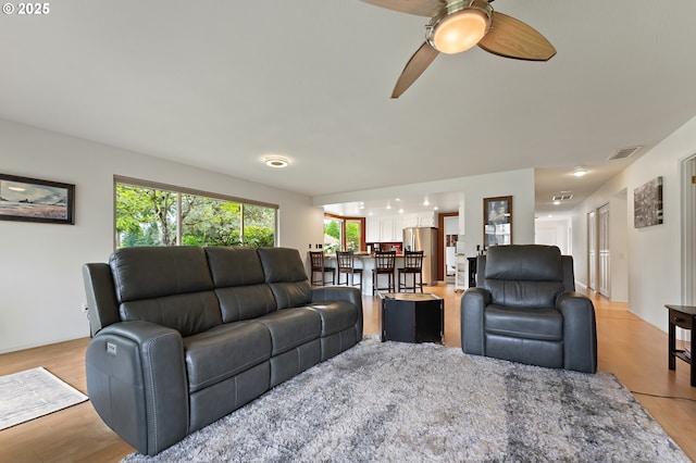 living area featuring a ceiling fan, light wood-style flooring, and visible vents