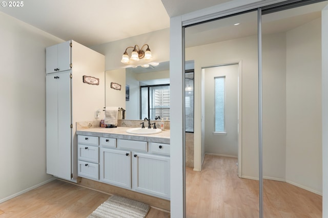 bathroom with baseboards, wood finished floors, and vanity