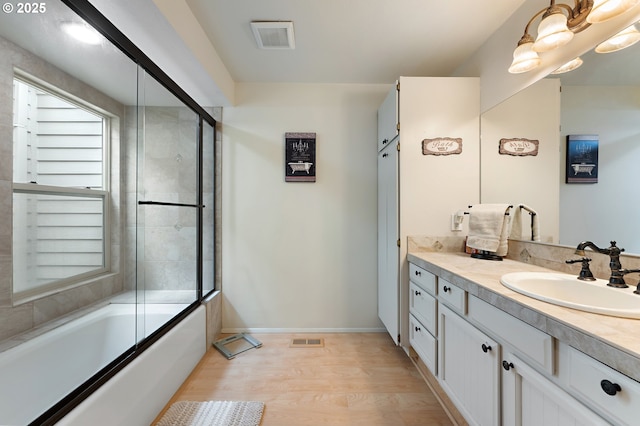 full bathroom with visible vents, enclosed tub / shower combo, wood finished floors, and vanity