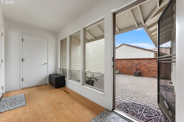 entryway featuring visible vents, brick wall, and light wood-type flooring