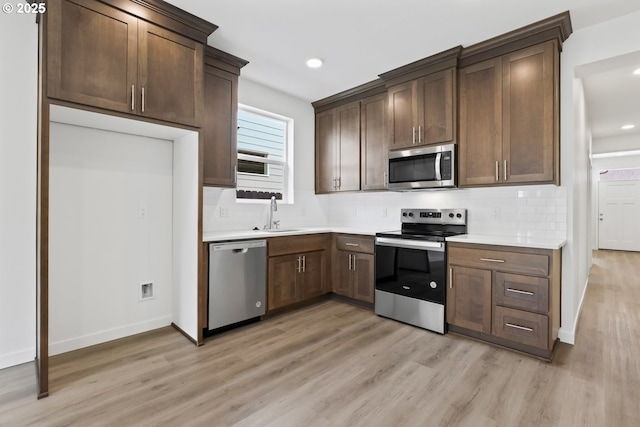 1912 NW 18th Ave, Battle Ground, WA 98604 - kitchen with light countertops, a sink, light wood finished floors, appliances with stainless steel finishes, and decorative backsplash