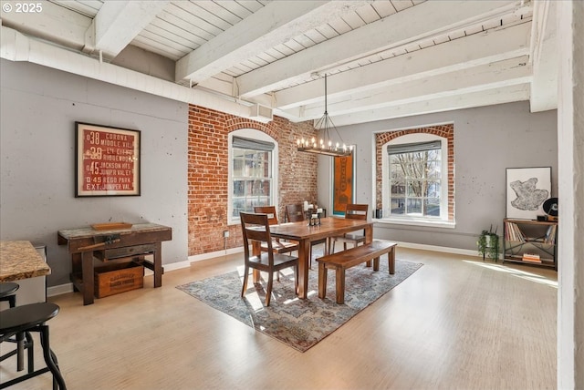 dining room featuring a notable chandelier, beamed ceiling, baseboards, and light wood-style floors