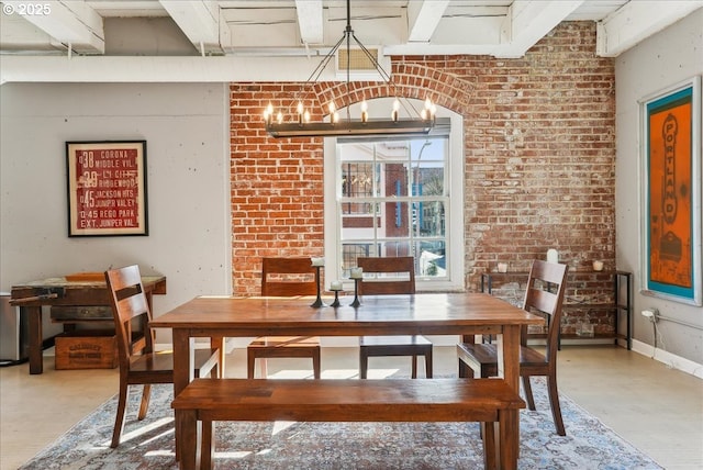 dining space with beam ceiling, baseboards, brick wall, and wood finished floors