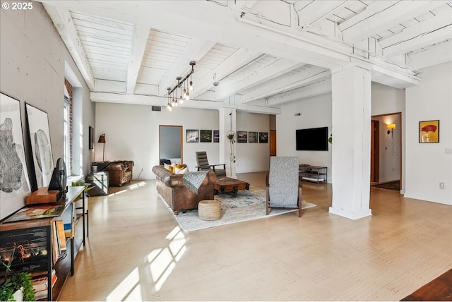 living area featuring visible vents, beam ceiling, and wood finished floors