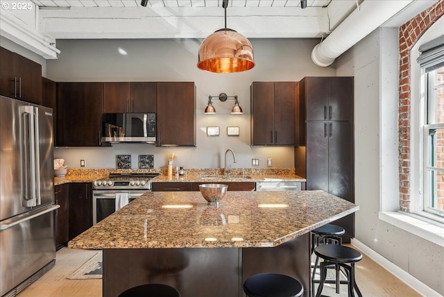 kitchen featuring stainless steel appliances, a breakfast bar, a sink, and dark brown cabinets