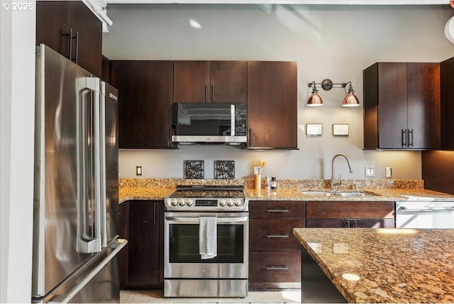 kitchen with stainless steel appliances, light stone counters, a sink, and dark brown cabinetry