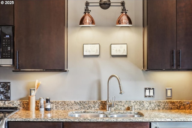 kitchen with dishwasher, light stone counters, a sink, and dark brown cabinetry