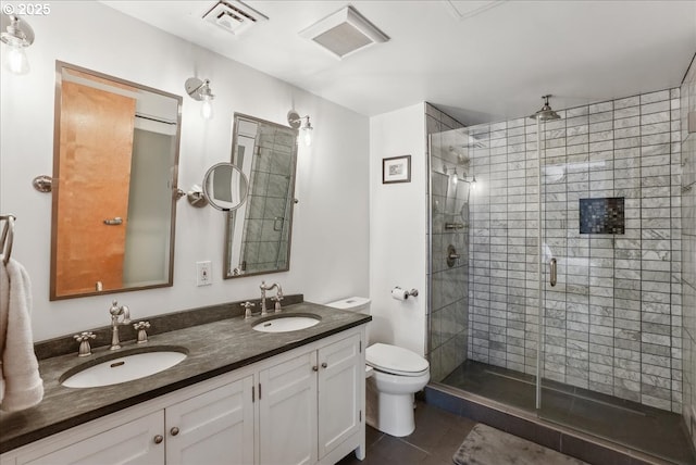 bathroom featuring a stall shower, visible vents, a sink, and toilet