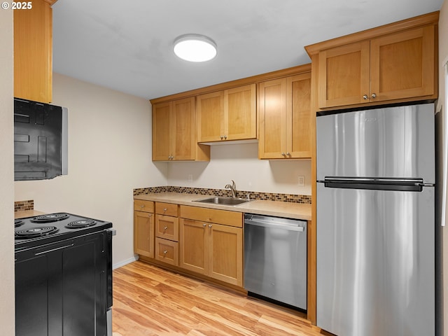 kitchen featuring light wood finished floors, appliances with stainless steel finishes, light countertops, and a sink