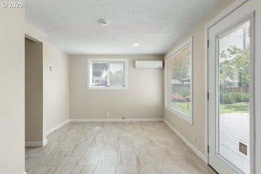 2065 Providence St, Eugene, OR 97401 - empty room featuring a wall mounted AC, a textured ceiling, and light marble finish flooring