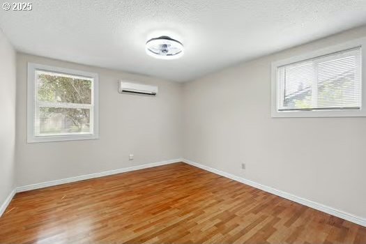 2065 Providence St, Eugene, OR 97401 - empty room with an AC wall unit, light wood-style floors, and a textured ceiling