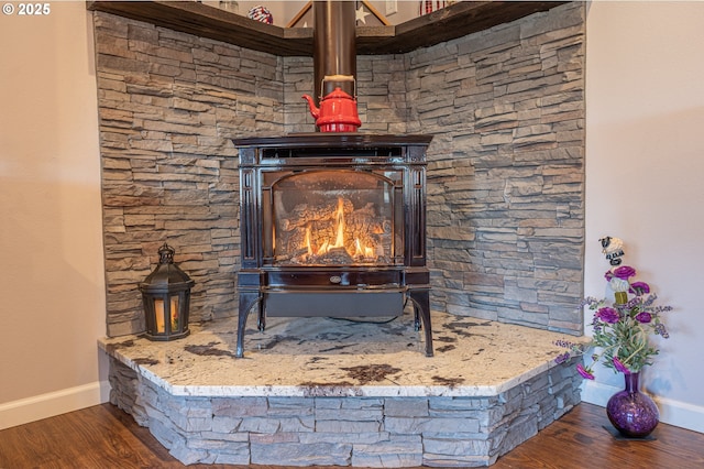 room details featuring a wood stove, wood finished floors, and baseboards