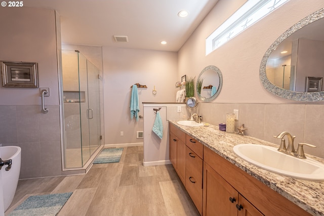 bathroom with wood finished floors, visible vents, a stall shower, and a sink