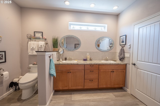 full bath featuring double vanity, wood finished floors, toilet, and a sink