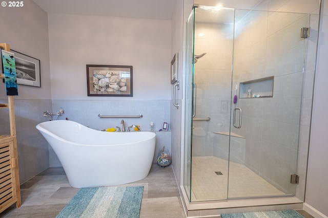 full bathroom featuring a freestanding tub, a shower stall, a wainscoted wall, and tile walls