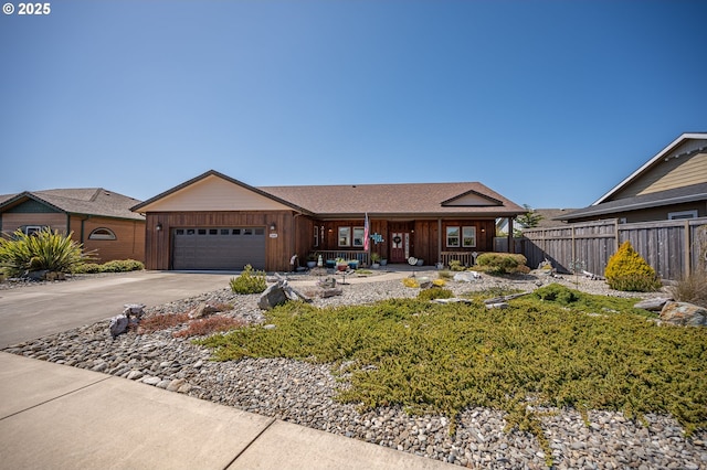 ranch-style home with driveway, board and batten siding, covered porch, an attached garage, and fence
