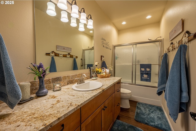bathroom with shower / bath combination with glass door, vanity, toilet, and wood finished floors