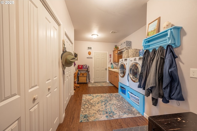 washroom with visible vents, wood finished floors, cabinet space, and washing machine and dryer