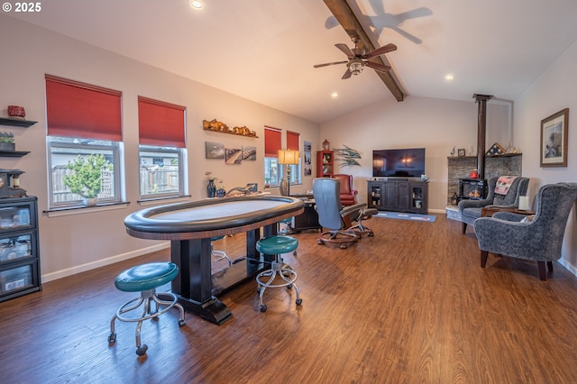 interior space with a wood stove, baseboards, wood finished floors, a ceiling fan, and vaulted ceiling with beams