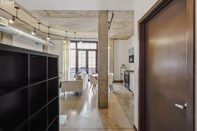 hall with track lighting and finished concrete floors