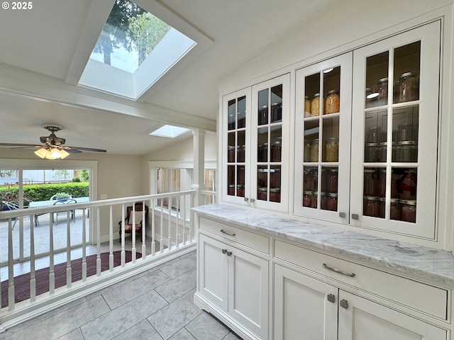hallway with a skylight, light tile patterned flooring, and vaulted ceiling