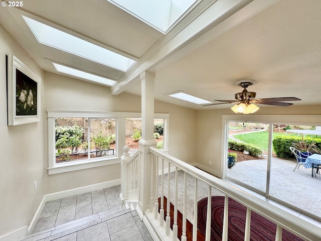hall featuring a skylight, baseboards, an upstairs landing, and tile patterned floors