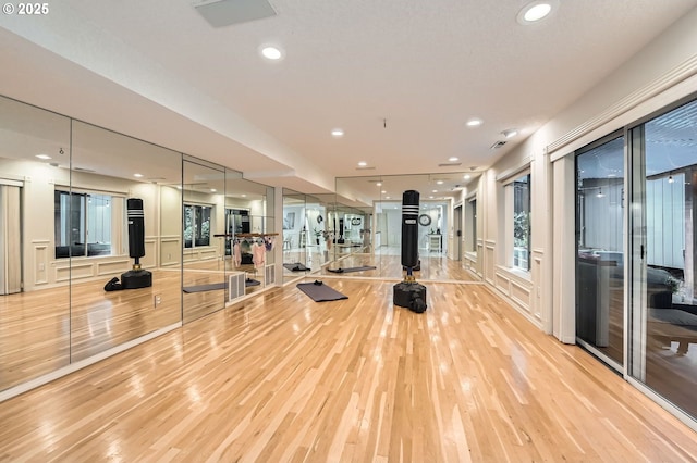 exercise room with light wood-type flooring and recessed lighting