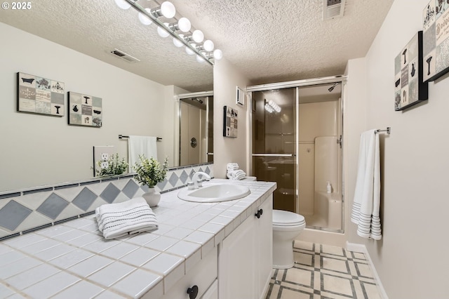 full bathroom featuring a shower stall, vanity, toilet, tile patterned floors, and a textured ceiling