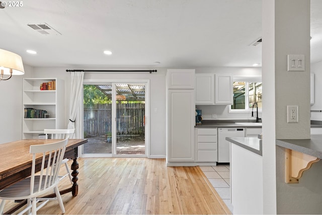 3370 Alder St, Eugene, OR 97405 - kitchen featuring white dishwasher, white cabinetry, light wood-style floors, dark countertops, and recessed lighting