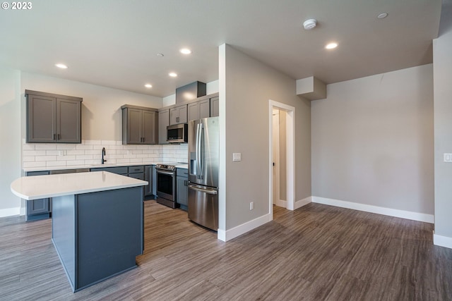 304 N Bridgeton Rd, Portland, OR 97217 - kitchen with stainless steel appliances, light countertops, backsplash, wood finished floors, and a center island