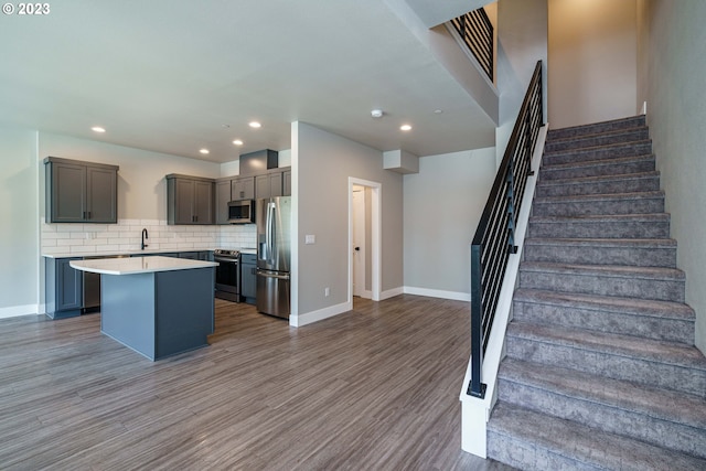 304 N Bridgeton Rd, Portland, OR 97217 - kitchen featuring stainless steel appliances, a kitchen island, wood finished floors, tasteful backsplash, and light countertops