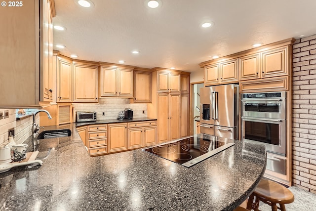 kitchen featuring a warming drawer, a sink, backsplash, appliances with stainless steel finishes, and a peninsula