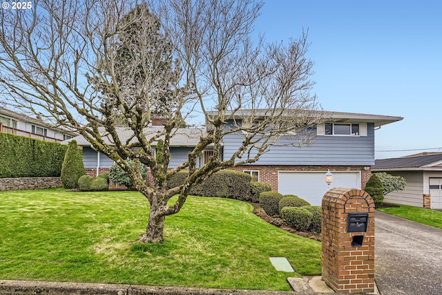 tri-level home with a garage, brick siding, concrete driveway, and a front yard