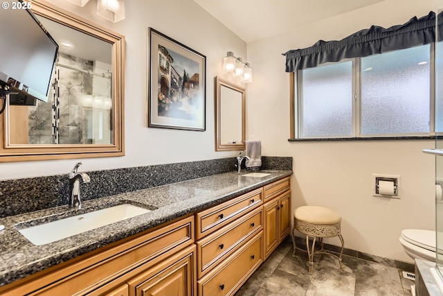 full bathroom featuring a sink, toilet, a stall shower, and double vanity