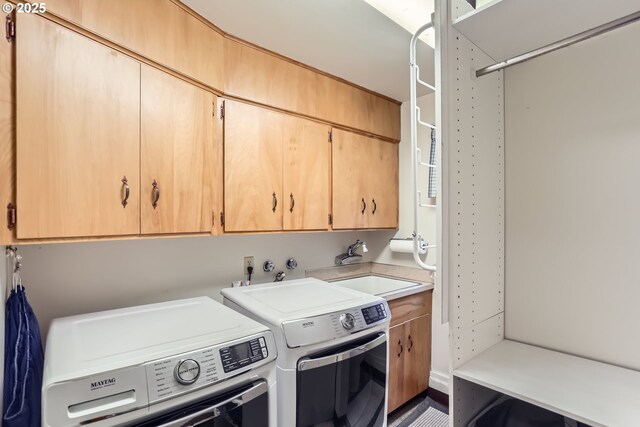 clothes washing area with washer and clothes dryer, cabinet space, and a sink