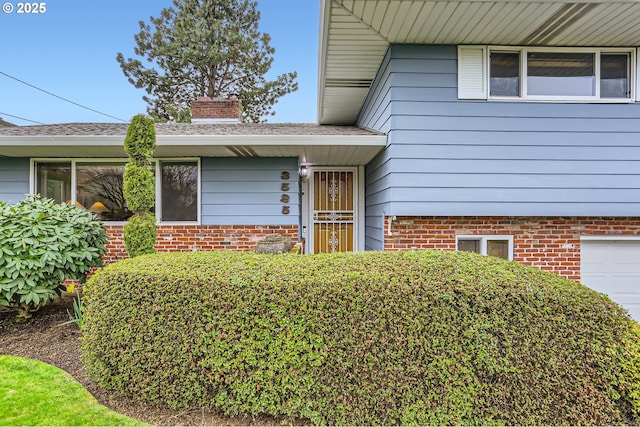 view of exterior entry featuring a chimney and a garage