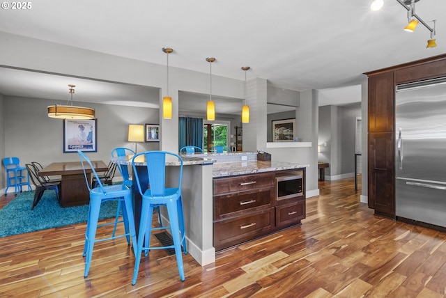 703 NW 94th St, Vancouver, WA 98665 - kitchen with stainless steel appliances, wood finished floors, a kitchen bar, dark brown cabinetry, and hanging light fixtures