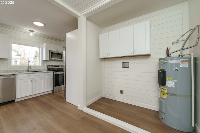 kitchen with sink, light hardwood / wood-style flooring, water heater, appliances with stainless steel finishes, and white cabinetry