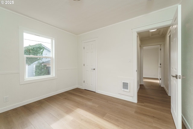 spare room featuring crown molding and light hardwood / wood-style floors