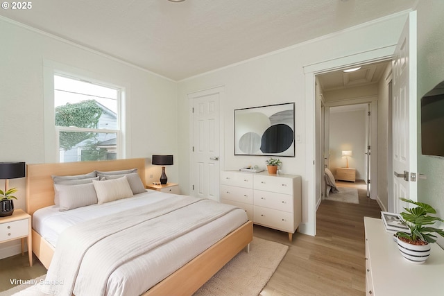 bedroom featuring crown molding and light wood-type flooring