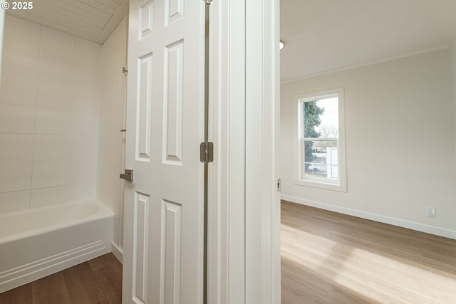 bathroom featuring wood-type flooring and tiled shower / bath